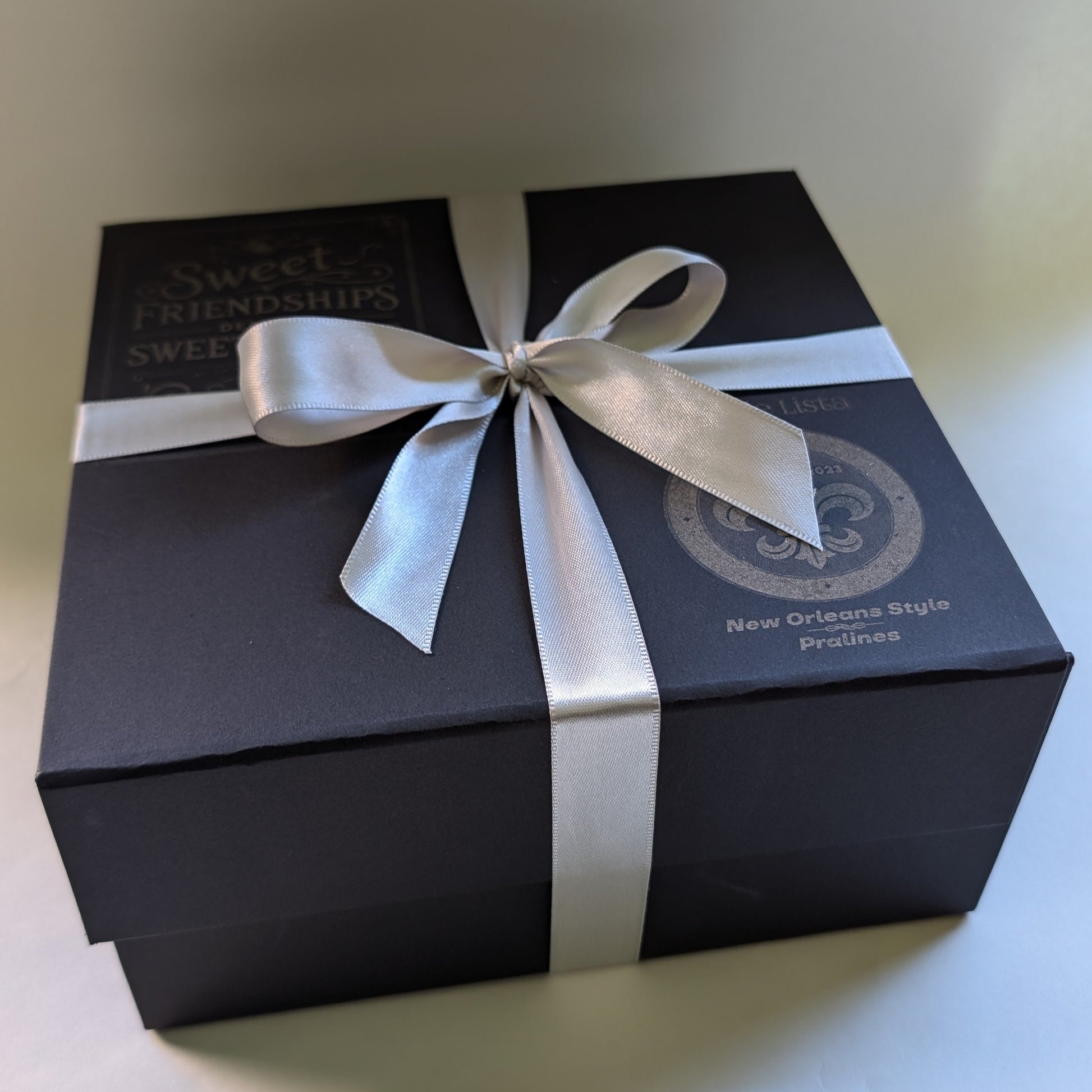 Black gift box with a white ribbon on a light background